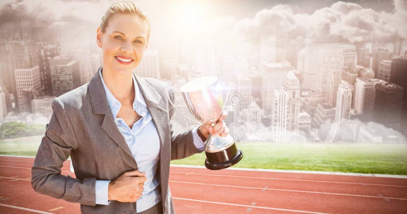 Composite image of successful businesswoman holding a trophy stock photo Composite image of successful businesswoman holding a trophy stock photo