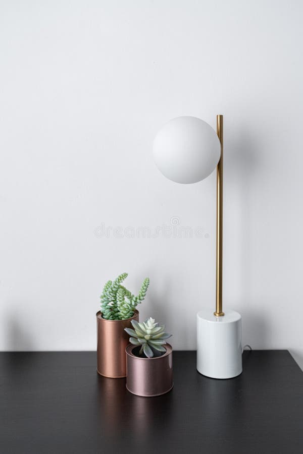 Composition of artificial plants copper vase and gold stylish table lamp in mid century modern design standing on black wooden top royalty free stock images Composition of artificial plants copper vase and gold stylish table lamp in mid century modern design standing on black wooden top royalty free stock images