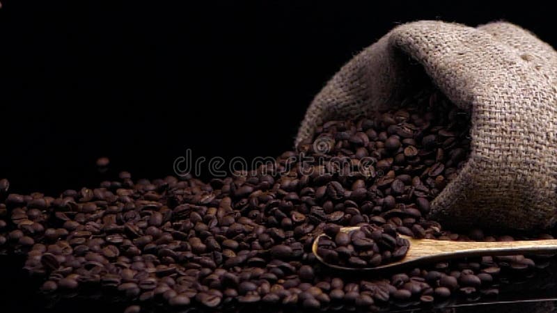 Composition from coffee beans. Black background decorated with bag with coffee beans, scoop with fragrant coffee beans.