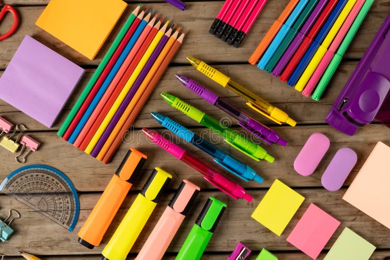 Composition of colorful crayons, pens, markers and other school tools on wooden surface. School equipment, tools, learning and creativity concept.