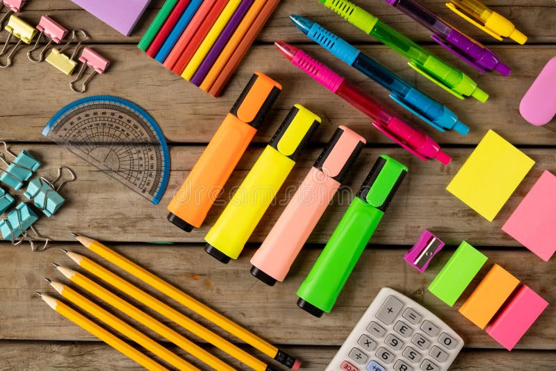 Composition of colorful crayons, pens, markers and other school tools on wooden surface. School equipment, tools, learning and creativity concept.