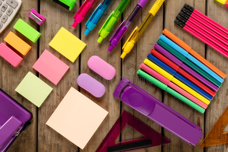 Composition of colorful crayons, pens, markers and other school tools on wooden surface. School equipment, tools, learning and creativity concept.