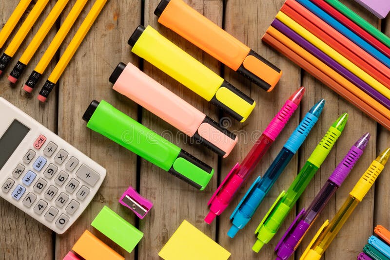 Composition of colorful crayons, pens, markers and other school tools on wooden surface. School equipment, tools, learning and creativity concept.