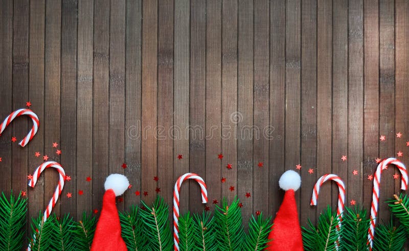 Composition de Noël d'une branche d'arbre, chapeau de Père Noël, étoiles de bonbons, cône de pin, sur fond de bois Le concept de photographie stock libre de droits Composition de Noël d'une branche d'arbre, chapeau de Père Noël, étoiles de bonbons, cône de pin, sur fond de bois Le concept de photographie stock libre de droits