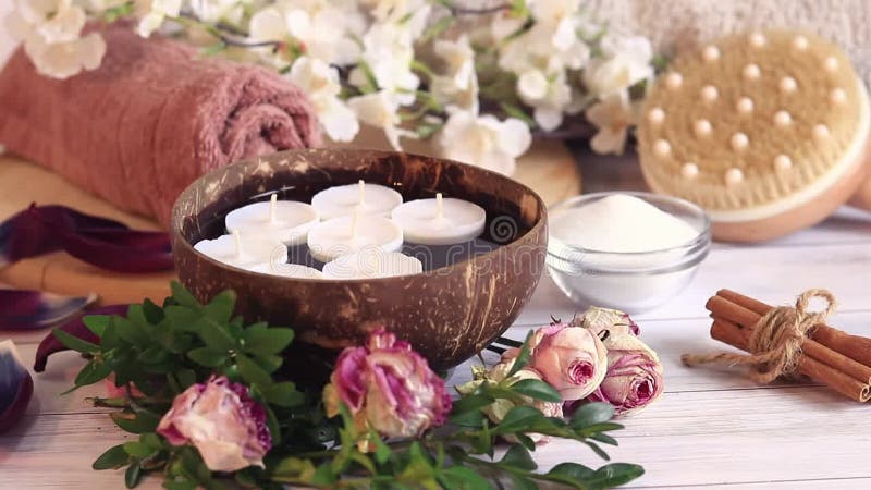 Composition du spa vidéo de fermeture. bougies dans l'eau. bol de coco avec bougies fleurs cannelle tubes de massage brosse et sel clips vidéos