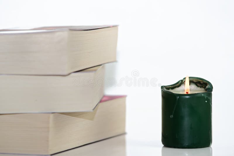 Green burning candle and pile of books against white background. Composition of green burning candle and pile of books against white background royalty free stock photo Green burning candle and pile of books against white background. Composition of green burning candle and pile of books against white background royalty free stock photo