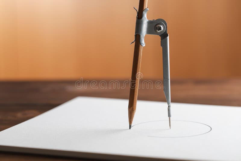 Composition with paper and drawing compass on wooden table. Drafting tool for geometry education and planning design stock photo