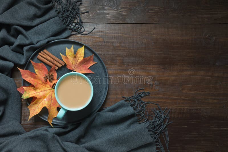 Composizione in autunno con la tazza di caffè, sciarpa calda delle foglie asciutte variopinte sul bordo di legno Copi lo spazio V fotografia stock libera da diritti