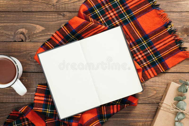 Composizione flatlay autunno Vista dall'alto su un libro con pagine vuote, sciarpa rossa a maglia, tazza di tè, scatola regalo su