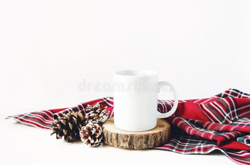 Winter still life composition. Blank ceramic coffee mugstanding on wooden cut board, pine cones and red checkered tartan plaid on white table background, Christmas traditional styled photo, mockup. Winter still life composition. Blank ceramic coffee mugstanding on wooden cut board, pine cones and red checkered tartan plaid on white table background, Christmas traditional styled photo, mockup.