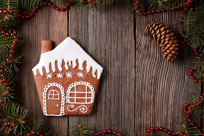 Gingerbread house cookie christmas composition in new year decorations frame on vintage wooden table background. Homemade traditional dessert icing recipe. Top view. Gingerbread house cookie christmas composition in new year decorations frame on vintage wooden table background. Homemade traditional dessert icing recipe. Top view