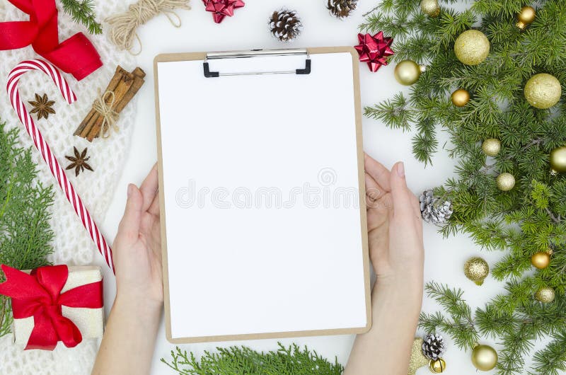 Composição do Natal do modelo ramos do abeto dos cones do pinho, caixa de presente, bolas douradas, doces no fundo branco Mãos da