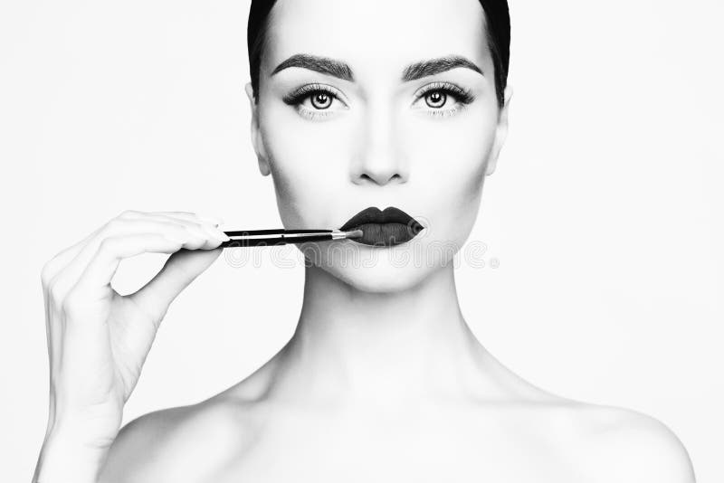 Black and white studio fashion photo of beautiful young lady applied lipstick. Perfect face makeup. Black and white studio fashion photo of beautiful young lady applied lipstick. Perfect face makeup