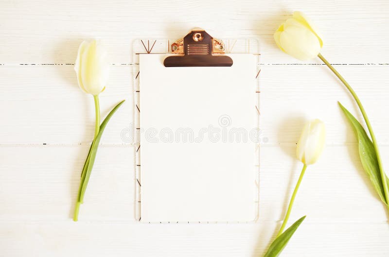 A composição feminino do desktop com a prancheta da folha vazia & as tulipas brancas na textura de madeira apresentam o fundo, co imagens de stock A composição feminino do desktop com a prancheta da folha vazia & as tulipas brancas na textura de madeira apresentam o fundo, co imagens de stock