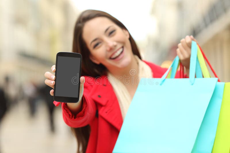 Comprador con los panieres que muestran el teléfono imágenes de archivo libres de regalías Comprador con los panieres que muestran el teléfono imágenes de archivo libres de regalías