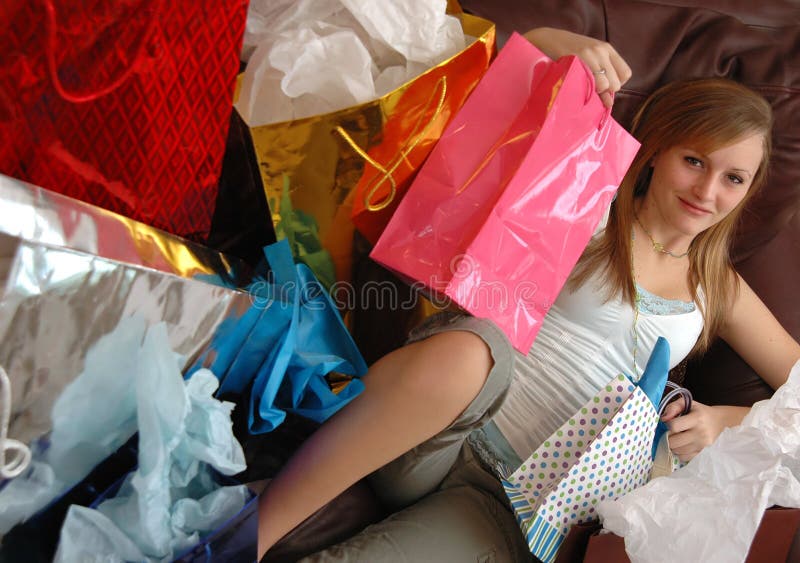 A teen girl lying back on a couch with lots of shopping bags surrounding her. A teen girl lying back on a couch with lots of shopping bags surrounding her.