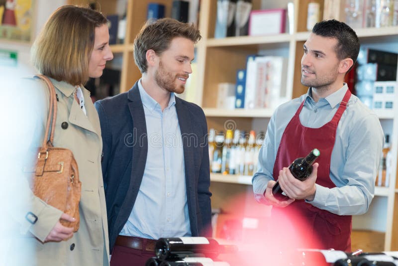 Compras felices de los pares en vinos de la compra del supermercado imagen de archivo libre de regalías Compras felices de los pares en vinos de la compra del supermercado imagen de archivo libre de regalías