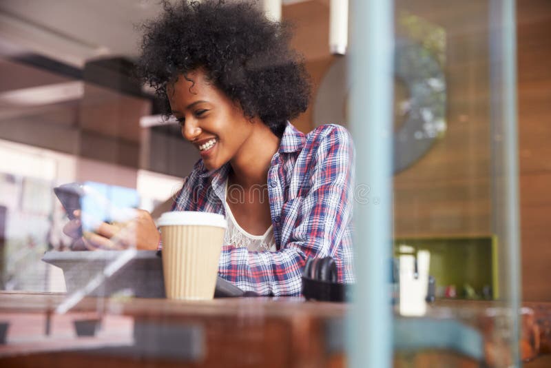 Businesswoman On Phone Using Digital Tablet In Coffee Shop. Businesswoman On Phone Using Digital Tablet In Coffee Shop