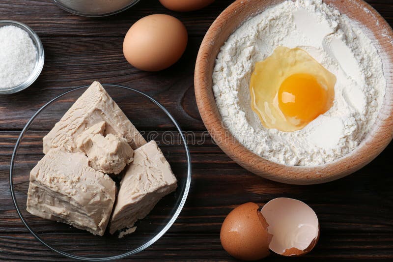 Compressed Yeast, Eggs, Salt and Flour on Wooden Table, Flat Lay Stock