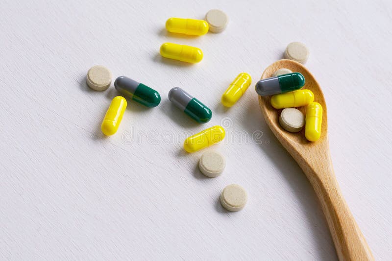 Comprimidos farmac?uticos sortidos, tabuletas e c?psulas da medicina na colher de madeira foto de stock Comprimidos farmac?uticos sortidos, tabuletas e c?psulas da medicina na colher de madeira foto de stock