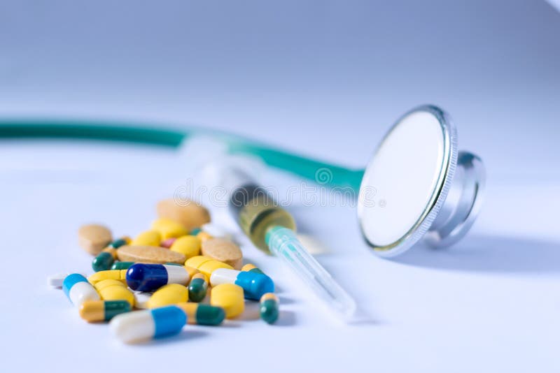 Comprimidos, tabuletas e cápsulas farmacêuticos coloridos da medicina com seringa e estetoscópio no fundo branco Conceito MÉDICO foto de stock Comprimidos, tabuletas e cápsulas farmacêuticos coloridos da medicina com seringa e estetoscópio no fundo branco Conceito MÉDICO foto de stock