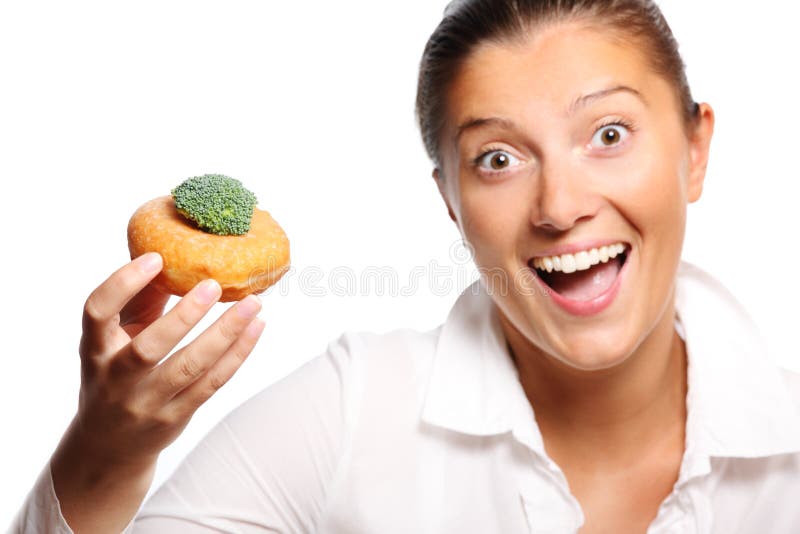 A picture of a young woman finding perfect compromise between eating a donut and broccoli. A picture of a young woman finding perfect compromise between eating a donut and broccoli