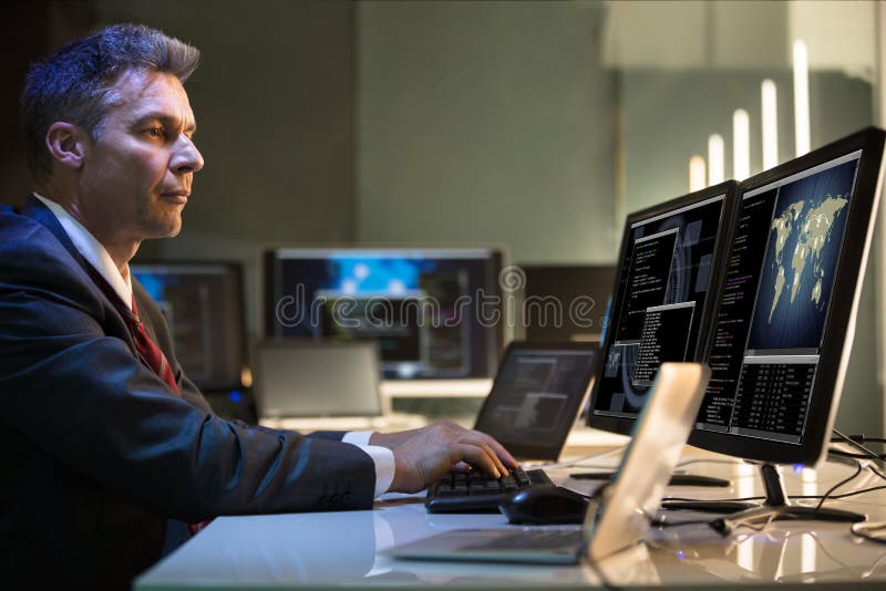 Computadores de Working On Multiple do homem de negócios imagens de stock Computadores de Working On Multiple do homem de negócios imagens de stock