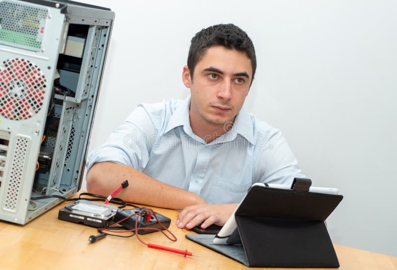 Computer di riparazione del tecnico del giovane fotografia stock libera da diritti Computer di riparazione del tecnico del giovane fotografia stock libera da diritti