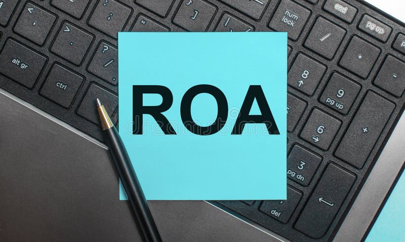 The computer keyboard has a pen and a blue sticker with the text ROA Return On Assets. Flat lay. Letters roa stock images, royalty-free photos and pictures