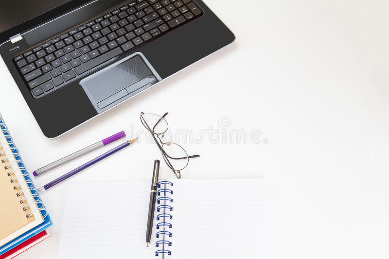 Computer laptop with notebooks, glasses, pen, pencil on white desk