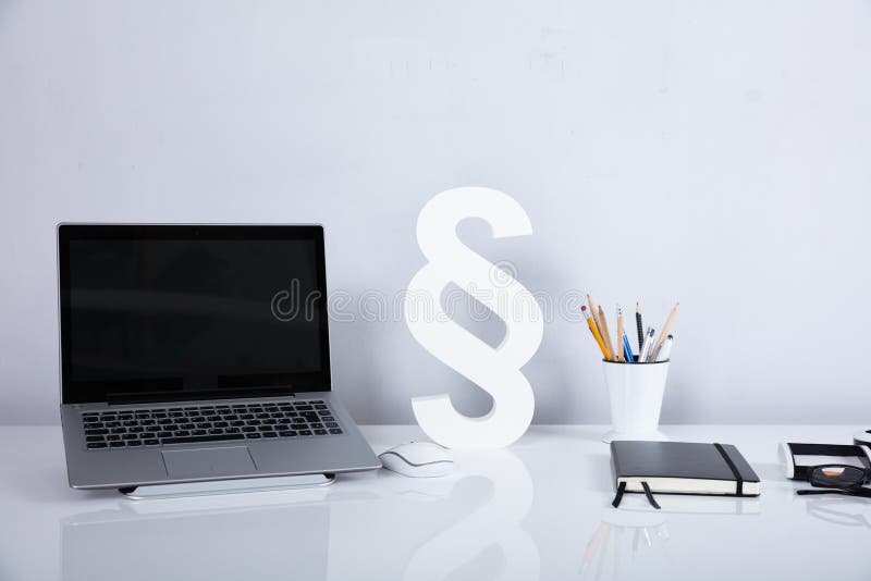 Computer portatile e simbolo di paragrafo sullo scrittorio riflettente fotografia stock