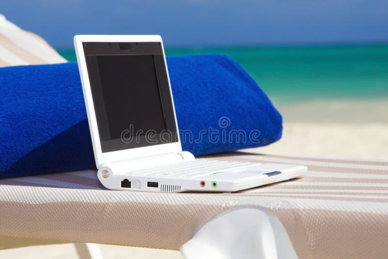 Computer portatile e tovagliolo sul longue del chaise della spiaggia fotografia stock libera da diritti Computer portatile e tovagliolo sul longue del chaise della spiaggia fotografia stock libera da diritti