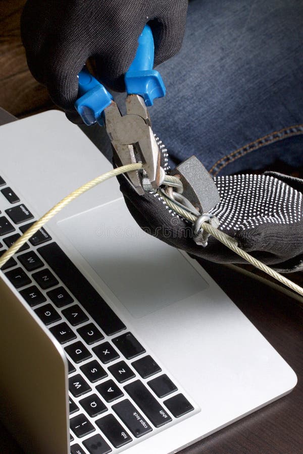 Computer security. Protection of access to data. The laptop is protected by a security cable and a lock. An attacker with gloves t stock photo Computer security. Protection of access to data. The laptop is protected by a security cable and a lock. An attacker with gloves t stock photo