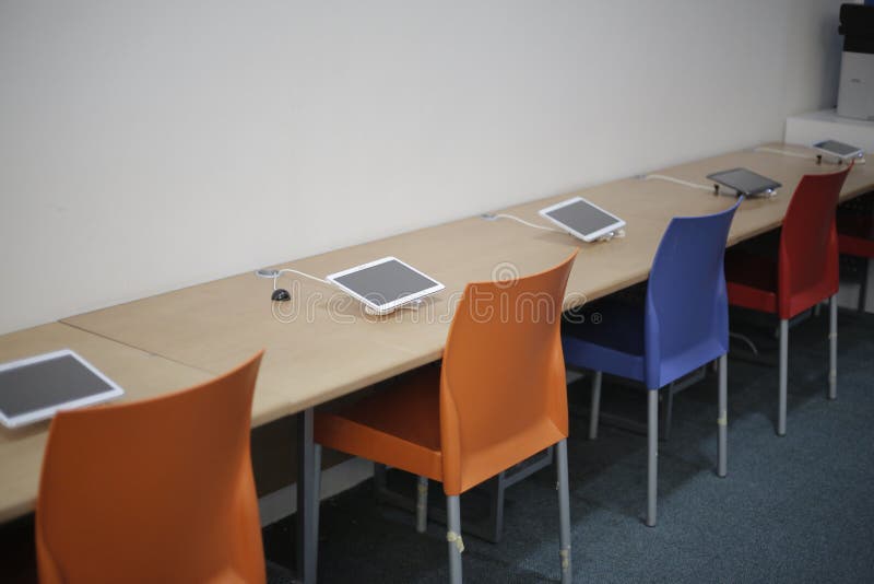 Computer tablets on a long desk in a classroom. Computer tablets on a long desk in a classroom.