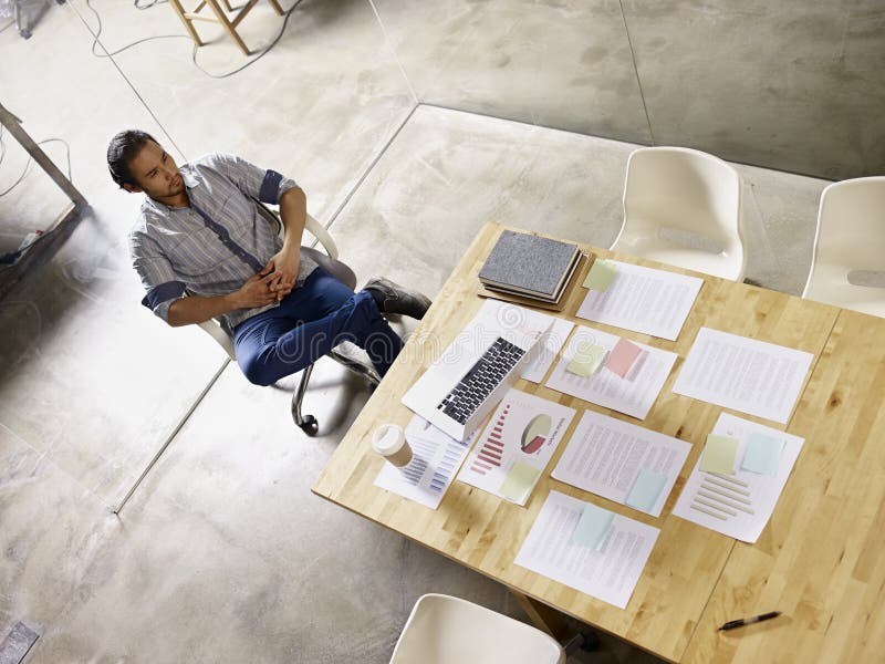 Comtemplando al hombre de negocios asiático que se sienta solamente en sala de reunión imagenes de archivo Comtemplando al hombre de negocios asiático que se sienta solamente en sala de reunión imagenes de archivo