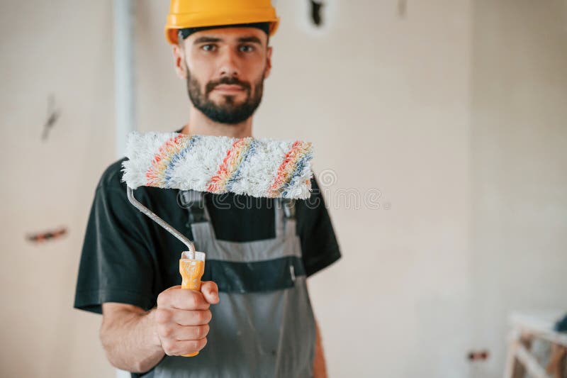 Con rotolo. l'uomo sta riparando nell'appartamento immagine stock libera da diritti