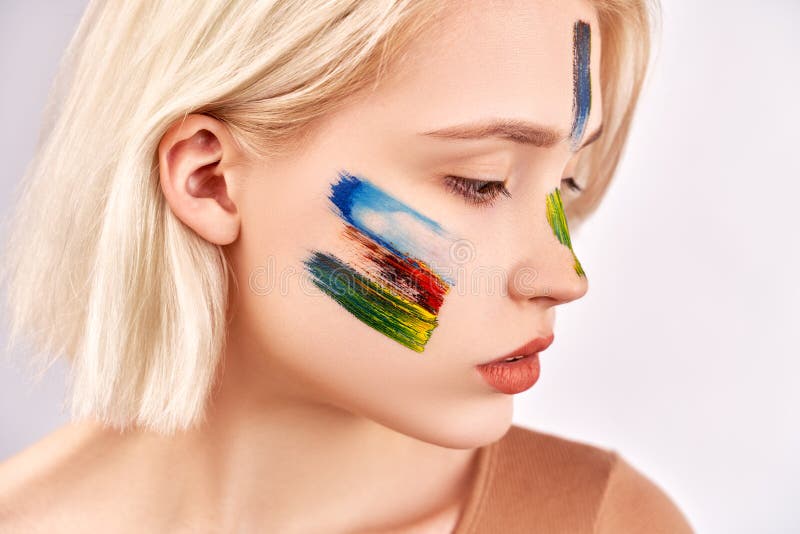 Conceito da arte da cara A mulher agradável com composição bonita da arte, tem o cabelo louro curto, poses contra o fundo branco foto de stock Conceito da arte da cara A mulher agradável com composição bonita da arte, tem o cabelo louro curto, poses contra o fundo branco foto de stock