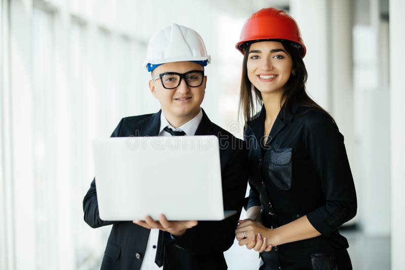 Conceito da engenharia e da arquitetura Coordenadores que trabalham em um terreno de construção que guarda um portátil, homem do foto de stock royalty free Conceito da engenharia e da arquitetura Coordenadores que trabalham em um terreno de construção que guarda um portátil, homem do foto de stock royalty free