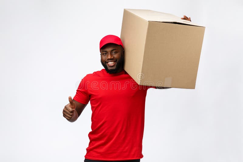 Conceito da entrega - caixa levando afro-americano considerável do pacote do homem de entrega Isolado no fundo cinzento do estúdi