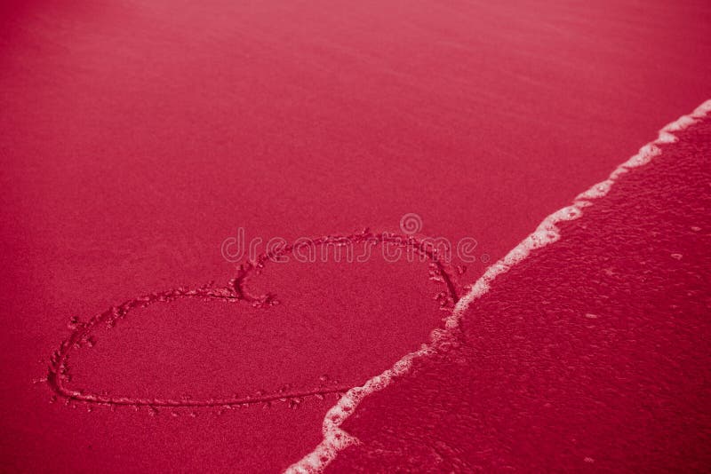 Concept of infidelity or fragile/fugitive/ephemeral love: heart drawn in sand being washed by the sea. Concept of infidelity or fragile/fugitive/ephemeral love: heart drawn in sand being washed by the sea