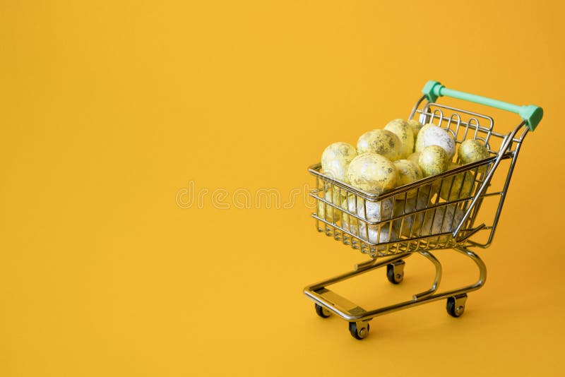 Conceito da venda da Páscoa Ovos da páscoa amarelos no trole de compra pequeno no fundo amarelo imagem de stock royalty free Conceito da venda da Páscoa Ovos da páscoa amarelos no trole de compra pequeno no fundo amarelo imagem de stock royalty free