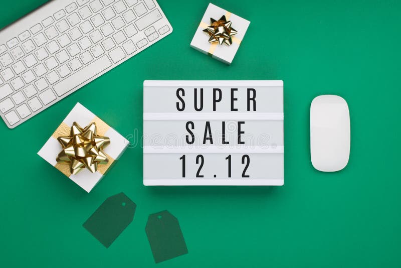 12.12 Super Sale text on white Lightbox, keyboard, computer mouse, gift boxes on  green paper background. Double 12 Mega sales day concept. Online shopping of China. Top view, copy space. 12.12 Super Sale text on white Lightbox, keyboard, computer mouse, gift boxes on  green paper background. Double 12 Mega sales day concept. Online shopping of China. Top view, copy space