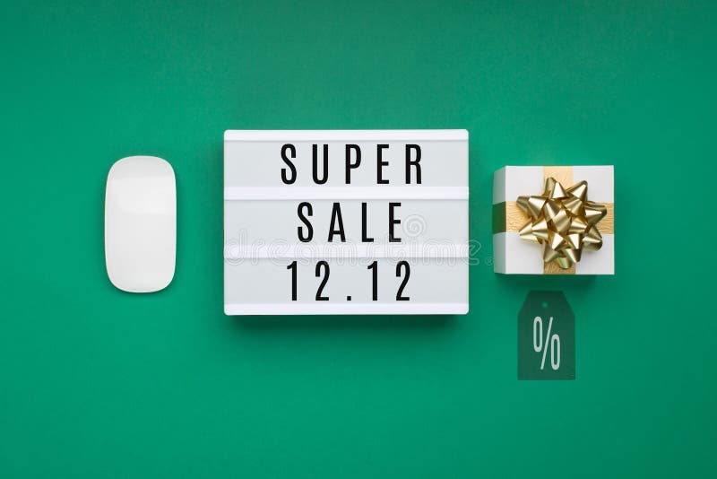 12.12 Super Sale text on white Lightbox, computer mouse, gift boxes, tag on green paper background. Double 12 Mega sales day concept. Online shopping of China. Top view, copy space. 12.12 Super Sale text on white Lightbox, computer mouse, gift boxes, tag on green paper background. Double 12 Mega sales day concept. Online shopping of China. Top view, copy space