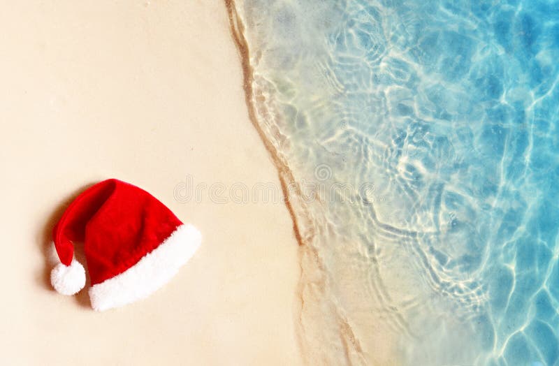 Conceito de feriados natalinos Vista de cima do chapéu de Papai Noel na areia de verão fotografia de stock royalty free Conceito de feriados natalinos Vista de cima do chapéu de Papai Noel na areia de verão fotografia de stock royalty free
