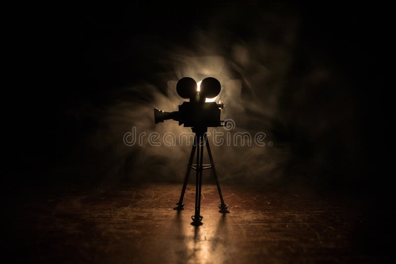 Conceito de filme. filme em miniatura sobre fundo tonto escuro com neblina e espaço vazio. silhueta de câmara de safra no tripé
