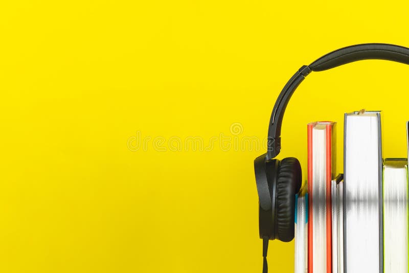 Conceito de livro de áudio auscultadores e livros sobre fundo amarelo