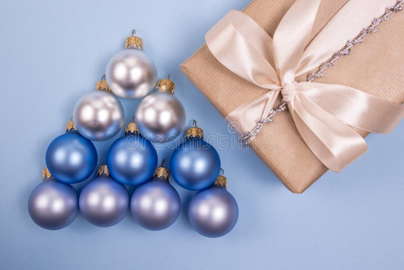 Conceito de Natal e Ano Novo As baubles de matta colocadas em forma de árvore de Natal num fundo azul claro com o presente imagem de stock Conceito de Natal e Ano Novo As baubles de matta colocadas em forma de árvore de Natal num fundo azul claro com o presente imagem de stock