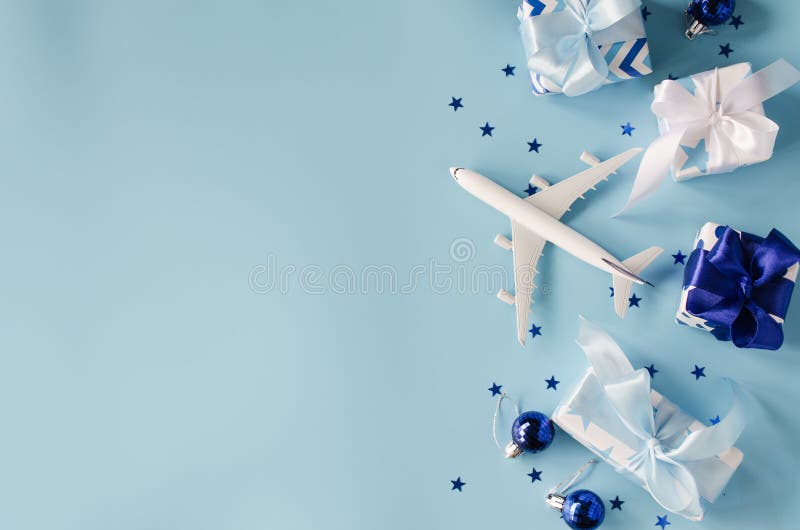 Christmas or New Year travel concept. Toy airplane with passports and gift boxes on blue background. Top view or flat lay. Copy Space. Christmas or New Year travel concept. Toy airplane with passports and gift boxes on blue background. Top view or flat lay. Copy Space