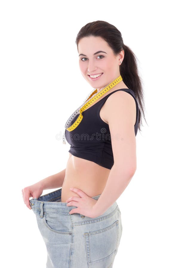 Conceito de Weightloss - mulher magro bonita feliz no iso grande das calças de brim fotos de stock royalty free Conceito de Weightloss - mulher magro bonita feliz no iso grande das calças de brim fotos de stock royalty free