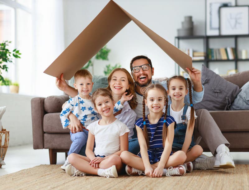 Conceito do alojamento e do internamento pai e crianças grandes felizes da mãe da família com telhado em casa